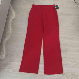 Röda kostymbyxor med fickor. Aldrig använda, lappar finns kvar på byxorna. 