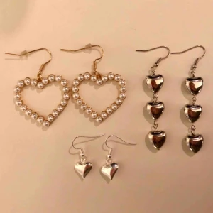  - 3 olika par örhängen med hjärtan. Det guldiga med pärlor kostar 80kr+frakt, de små silvriga kostar 40kr+frakt och de med flera hjärtan kostar 60kr+frakt. Nickelfria och oanvända!