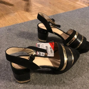  - Snygga sommarskor med bred klack men en linje i guldfärg som likaså går över foten. Och rem runt vristen för en lite sexylook samt stöd såklart 