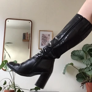  - Helt oanvända klackskor i svart läder! Jättesnygga till både kjol och byxor.  Klackhöjd: 9 cm, omkrets på skaft: 17x2 cm.  Frakt tillkommer om inte möte i Sthlm bestäms. 