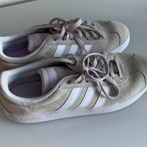 Adidas skor  - Säljer dessa helt nya, aldrig använda, jätte fina adidas skor i stl 38 2/3. Dom är impregnerade och gjord av mocka. Skon har, som ni kan se på bilden, jätte fina rosa detaljer och har en typ av beige/grå färg. Köpta för 499 och säljer för 250, är du intresserad då tveka inte att höra av dig, priset kan alltid diskuteras🥰 Frakten är inte inkluderad :)