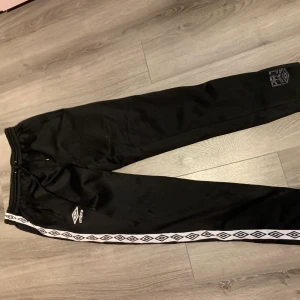 Umbro mjukisbyxor  - Svarta umbrobyxor med märkesstreck på sidorna, samma som kappas byxor endast annat märke