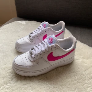 Nike Air Force 1 - Vita Nike Air Force 1 med rosa och ljusblå detaljer. Använda någon enstaka gång, säljer då de är försmå. 