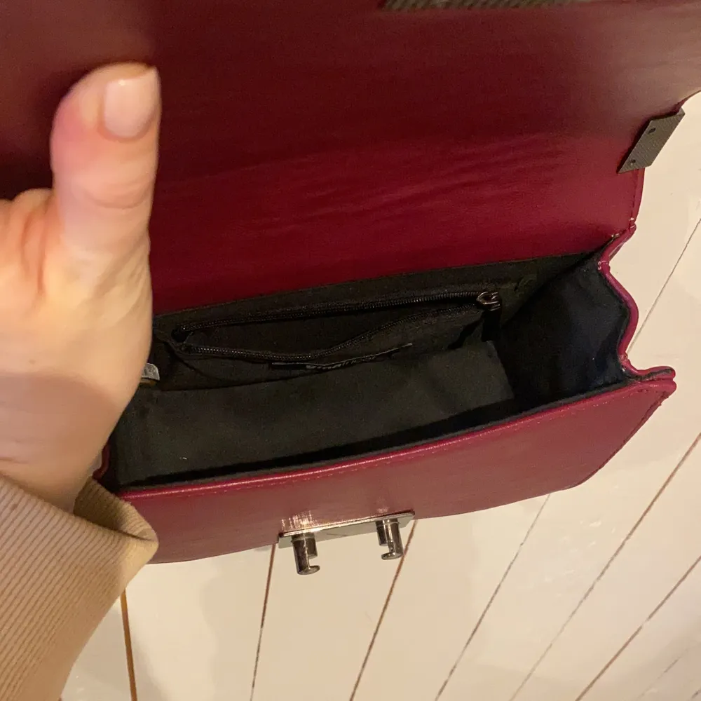 Axelbands väska som inte kommer till användning. Färgen är en blandning mellan rosa/röd. Väskor.