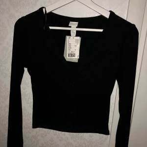 H&M topp - En svart långärmad topp men knappar från H&M. Köpte för jag trodde den skulle passa men den satt lite konstigt i ryggen på mig. Så alltså vara testat, skick 10/10. Säljer för samma pris + frakt 