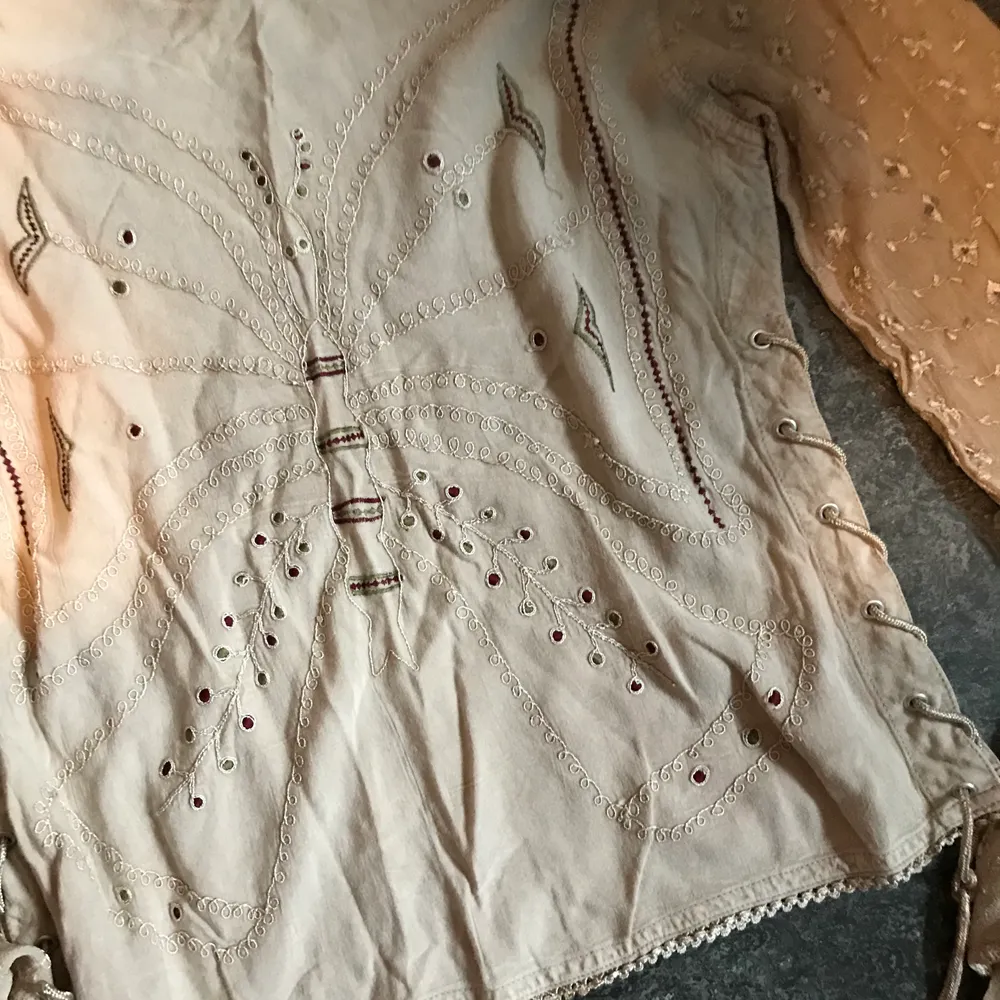 En beige långärmad tröja med Broderings detaljer i form av en fjäril på framsidan och snörning på sidorna. Kan mötas upp i Stockholm eller posta. Frakt 44kr. Meddela mig om eventuella frågor . Tröjor & Koftor.