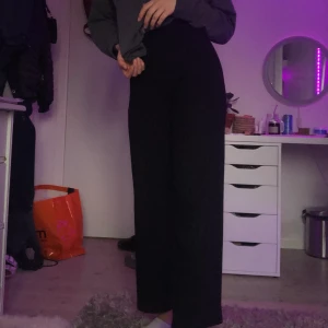 Gina svarta byxor - Svarta ribbade byxor från gina. Säljer pga för små. Stretchiga och är lite utsvängda längst ner. Köparen betalar för frakt och endast betalar med swish.