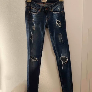  - Ett par jeans-färgade jeans som har hål vid knäna och högre upp på benet.  Använda ett fåtal gånger. +frakt  