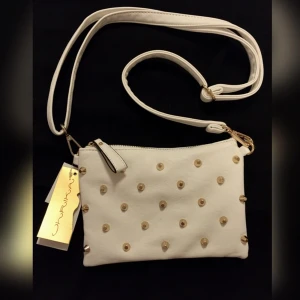  - Ulrika väska i vitt skinn, aldrig använd med prislapparna kvar. Trubbiga metallnitar som design och fem fack.