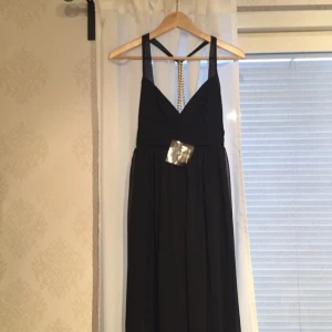  - Svart långklänning från Nelly Trend. Halterneckmodell med guldkedjor i ryggen. Aldrig använd, prislappar kvar. 
