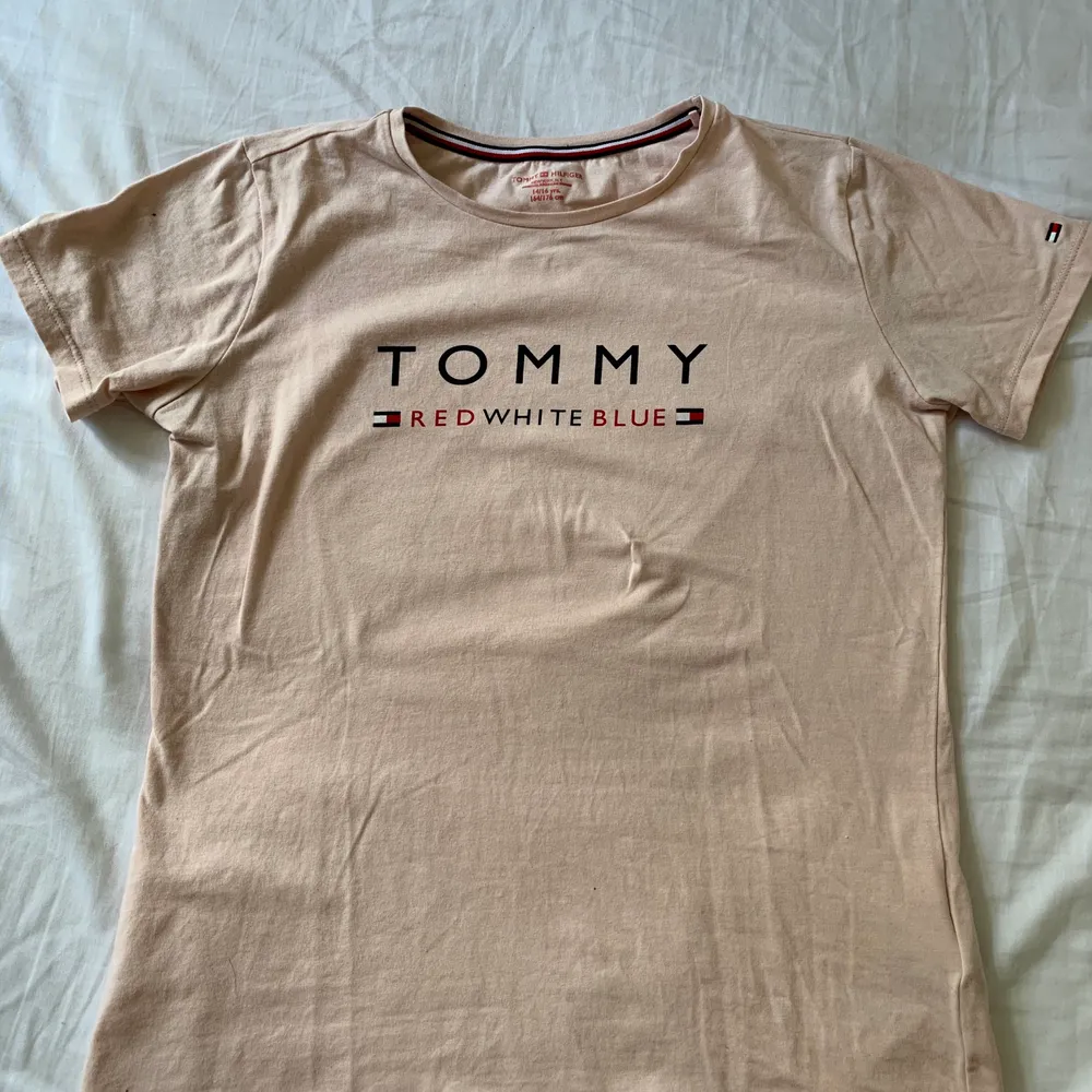 Tommy Hilfiger t-shirt i nuderosa färg i storlek 164/176. Knappt använd. Köparen står för frakten!🎀. T-shirts.
