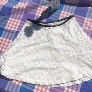 Virkad kjol - Vit virkad kjol från Gina Tricot, med vit underkjol. Svart kant överst och dragkedja baktill. 