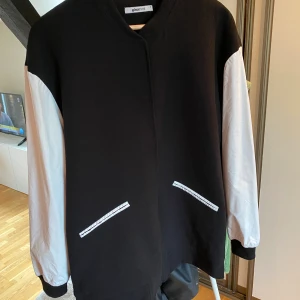 Jacka med ärmar i läderimitation  - Jacka från ginatricot. Lite längre i modellen men vita ärmar i läderimitation. 