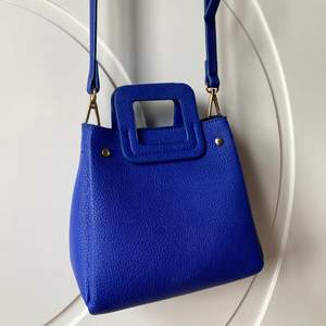 Väska från Pull & Bear i stark blå färg med guldiga detaljer.Axelremsband går att justera i längd. Skick: sparsamt använd med en del slitage i kant (se bild). Storlek: 18x7 cm, djup: 9 cm. 