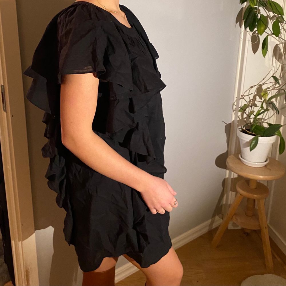Svart tunnare klänning med stora fina volanger- material i bomull. Jättefin till alla årstider; antingen till sandaler, stövlar, eller klackar! Klänningen har knapp baktill och en mindre öppen yta i ryggen. Jag har vanligtvis S och på mig sitter den lösare, storleken är L och därav passar den både M och L. Går såklart att stryka till. . Klänningar.