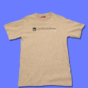 Champion University-tee - Färg: Grå/mörkblå/vit.                                                                   Storlek: M (pit to pit 47cm).                                           Skick: 8/10 Bra vintage skick.                                                    Detaljer: Broderad logga på ärmen.                                         Tar bud från 50kr,köp nu: 120kr. Frakt tillkommer (63kr). 