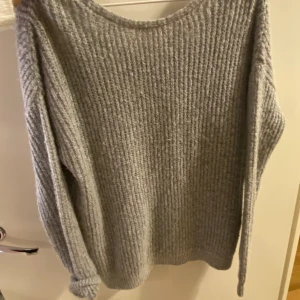 Grå stickat tröja med ryggen öppen - Stilren stickat tröja i grå, ryggen öppen, man kan knyta där bak. Så himla fin till ett par mom jeans eller tighta jeans, så snyggt! Använd ett fåtal gånger. 