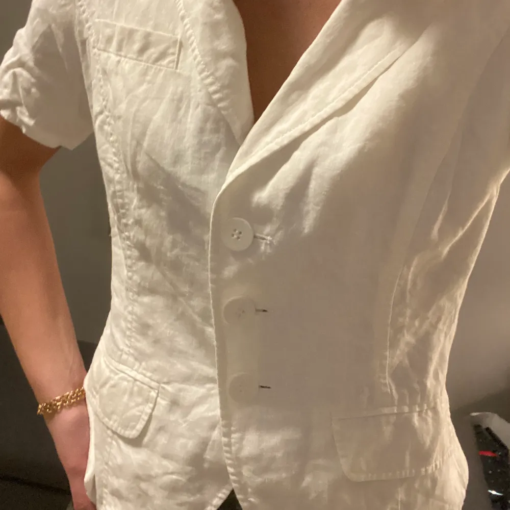 Säljer denna vita kortärmade skjortan, den knäppas av 3 knappar med en figurform . Skjortor.