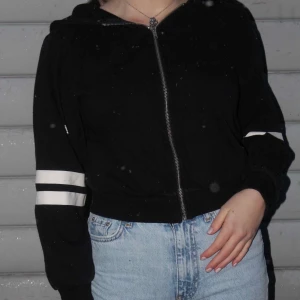 Svart Hoodie - Säljer den här skit snygga svarta hoodien! Den är lite större i armarna och har även 2 coola vita streck på ena armen🤩 Den är i bra skick! Köparen står för frakt💞 (OBS dom vita prickarna på bilden är snö)