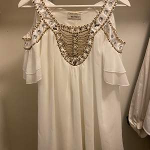 En vit kort klänning med guldetaljer