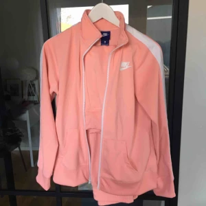 - Ett rosa set från Nike.  Storlek XL i barnstorlek (vilket är som XS/S i damstorlek). Nike-loggan på överdelen är minimalt färgat på N:et (se bilder).