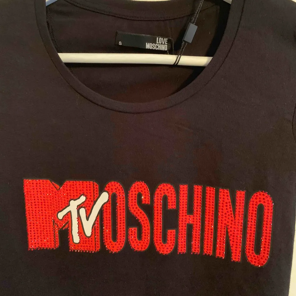Oanvänd märkes t-shirt från MOSCHINO för tjejer Storlek: S  —— OBS: KÖPAREN STÅ FÖR FRAKTEN! - Frakt med spårnummer kostar 63kr. T-shirts.