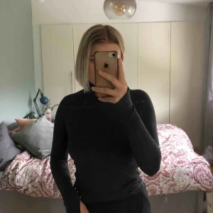  - Mörkgrå polo från Zara med guldknappar samt slits på ärmslutet