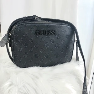 En svart superfin GUESS Crossbody och Axelremsväska. Sparsamt använd, är som ny.  - Svart snygg, stilren GUESS Crossbody eller axelremsväska. Som ny. Använd sparsamt. Inköpt i Feb 2020. Nypris 1300:- jag vill ha 270:-. Ej prutbart. Du swishar innan skick. 