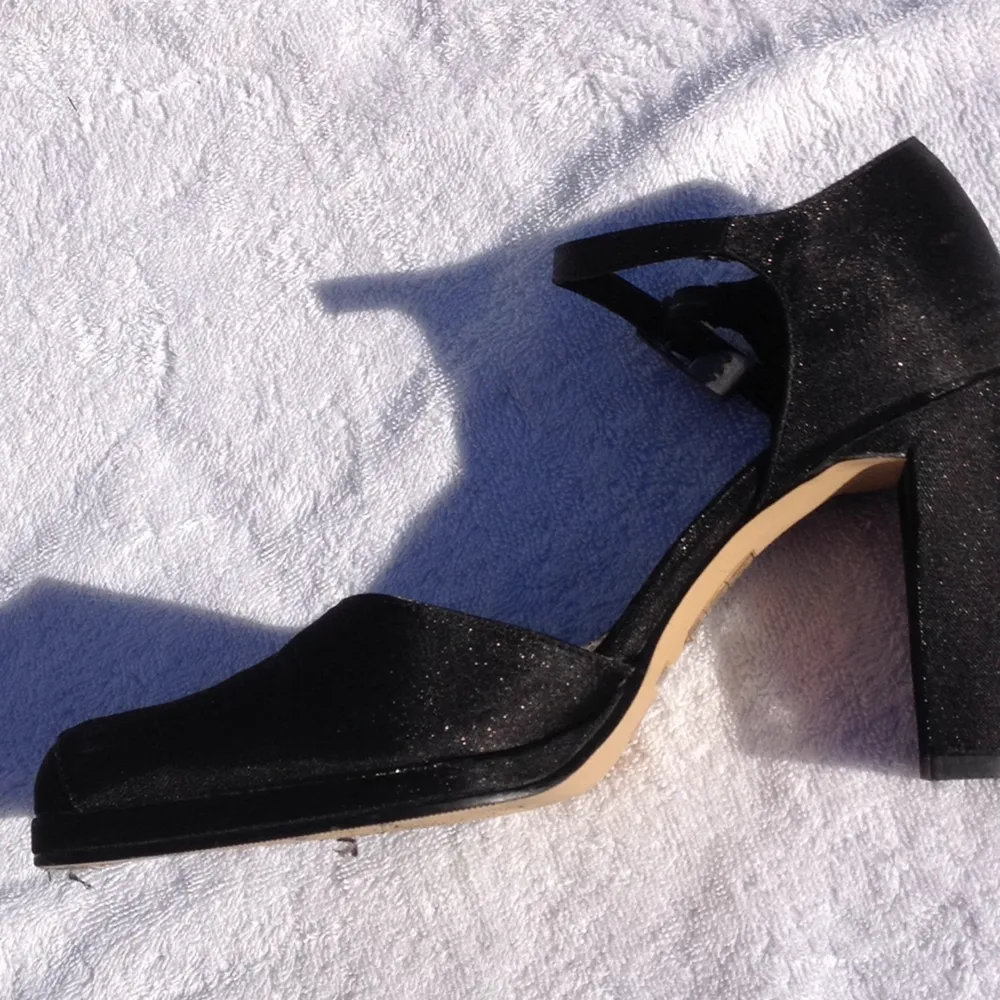 Svarta glittriga högklackade skor med fyrkantig tå och smal 10 cm hög klack. 
Smalt spänne vid vristen. Märke Elle. Tillverkade i Vietnam. Inköpta år 2000. Fint skick, knappt använda. Perfekt till festklänningen! . Accessoarer.