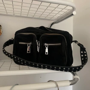 Noella Väska - Noella väska i storlek medium. Bra skick förutom att piggen till dragkedjan släppt och att ena kedjan på fickan har släppt i färgen, därav priset. 