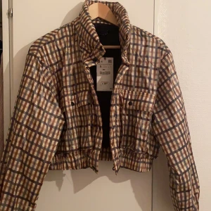 Rutig croppad jacka - Säljer nu denna jättesnygga croppade jackan från Zara. Säljes pga att jag tyvärr inte fått användning av den. Den e supersnygg och perfekt nu till tidig vinter!! Helt oanvänd med prislapp kvar. Kontakta mig för mer bilder/information. Kan mötas upp och leverera men köparen står för frakt. Nypris ca 25 €.