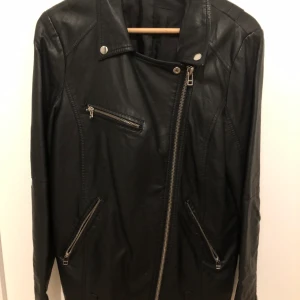 Skinnjacka från Cubus storlek 38 - Skinnjacka från Cubus storlek 38. Lite sliten vid kragen. Upphämtning på Lidingö. Ej äkta skinn.