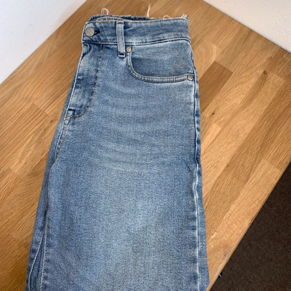 Ett par ljus blåa croppade jeans med råa kanter i bensluten. Jeansen är högmidjade och sitter ganska tight, lite små i storleken sitter som s/m.                                                      Jeansen är från GLOBALFUNK Denmark. Dessa Jensen är knappt använda, bara nån enstaka gång, så de är som nya. Köpte jeansen för 799 kr, säljer de nu för 299 kr + frakt. . Jeans & Byxor.