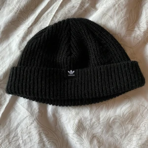 Adidas beenie/mössa - Supersnygg adidas beenie som jag inte använt då den är lite för liten på mig 🤯 skönt mjukt stickat/ribbat material, 10/10 skick. Frakten är spårbar och inkluderad i priset 🤼‍♂️