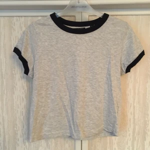 Grå t-shirt med mörkblå detaljer  - En supersnygg grå t-shorts med mörkblå ärmar och krage. Använd en gång pga för liten. St 36/38.