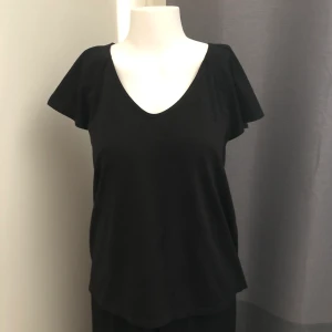 Topp Rules by Mary - Svart topp/ T-shirt med liten öppning i ryggen från Rules by Mary. Oanvänd. Storlek S.