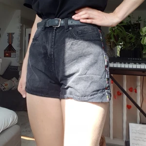 Jeansshorts - Jättefina svart/grå jeansshorts med färggranna broderade detaljer på sidorna. Väldigt bekväma och passar nästan till allting. Jättesnyggt att matcha färgen på broderit med sin topp!! Ganska använda men fortfarande gott skick. 