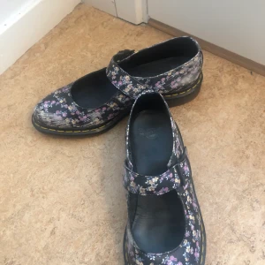 Dr. Martens floral/blommiga mary janes - Dr.martens ’Mary Janes’ som köptes för flera år sedan men har använts ganska sparsamt. Helt okej skick men mönstret/färgen har nötts bort vid hälarna och inre sidan av skon. Förutom det är skorna fräscha, och det slitna mönstret ser mest lite vintage ut!