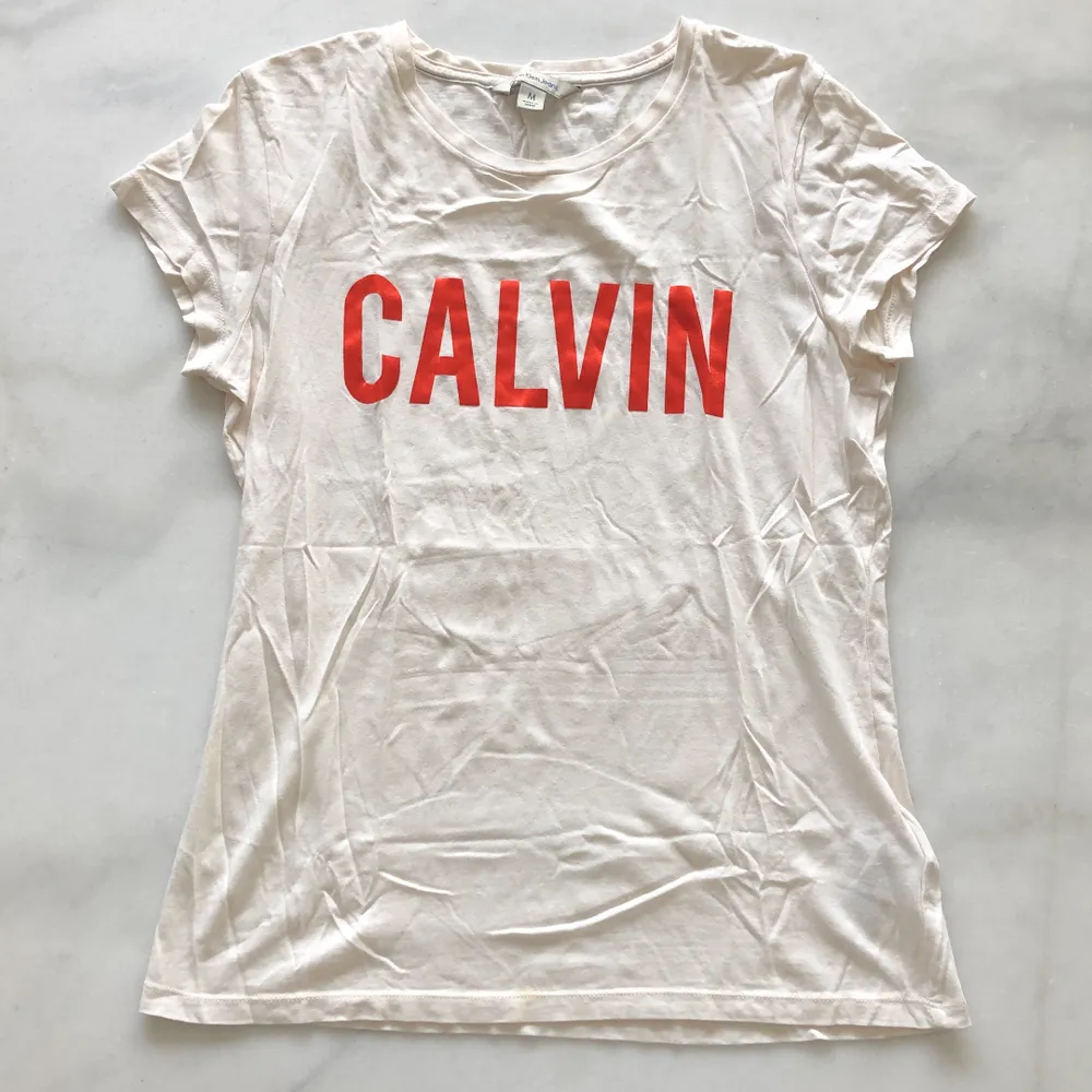 Offwhite Calvin T-shirt med röd glansig text. Använd ca 2 gånger. Liten fläck vid nedre sömmen se bilder. Frakten är inräknad i priset!. T-shirts.