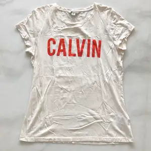 Offwhite Calvin T-shirt med röd glansig text. Använd ca 2 gånger. Liten fläck vid nedre sömmen se bilder. Frakten är inräknad i priset!
