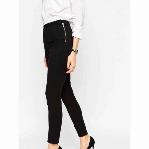  - Svarta kostymbyxor med hög midja och guldig dragkedja i sidan samt på bakfickan. 