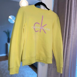 Collagetröja från Calvin Klein - Gul Collagetröja från Calvin Klein med vitt och rosa tryck. Använd en gång så väldigt bra skick, samt väldigt skön och mjuk på insidan. Köptes för 700kr, såklart äkta.