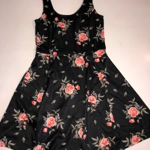 Klänning från H&M - Klänning från H&M i storlek 36. Använd 2-3 gånger. Svart med rosa blommor & gråa blad.