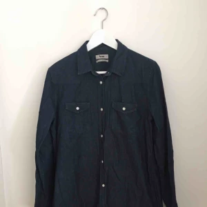  - En blå Jeans-skjorta från Acne.