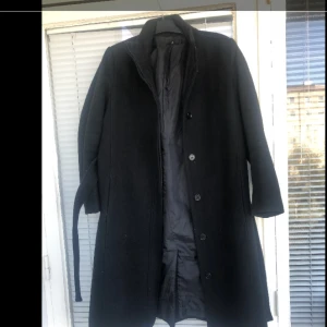  - Svart, fodrad kappa i mycket fint skick säljes. Endast använd en höst, från Åhléns. Strl: 38, upplever dock den mer som en one size då sen sitter snyggt ”oversize” på mig som normalt är strl S. 