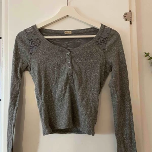  - Melerad grå croppad tröja från Hollister, storlek S. Fina spetsdetaljer 🌸 Betalas med swish och köparen står för frakten 😊