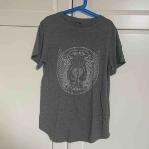  - En grå kortärmad metal tröja som är väldigt stretchig.