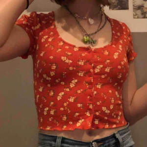  - Asfin orange topp med gula blommor på! sitter skitbra och tyget är rätt stretchigt 🧡 den är hyfsat croppad och perfekt för sommaren! 