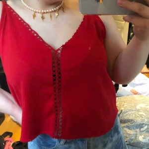  - Ett rött linne med en fin detalj längs med tröjan. Är väldigt bekväm och bra till sommaren, passar bra till allt och har justerbara band! (Den är ganska kort men är längre ner än naveln)  