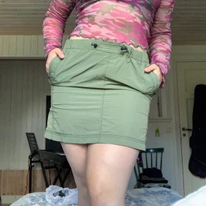 Grön kort kjol från Urban outfitters - Kjol från Urban Outfitters med resår i midjan. Ett av snörena har gått av men jag har löst det genom att knyta ihop det trasiga snöret och stoppat in det (bild 2), vilket gör att det inte syns att det är sönder. Skriv om ni vill ha fler bilder. Fri frakt